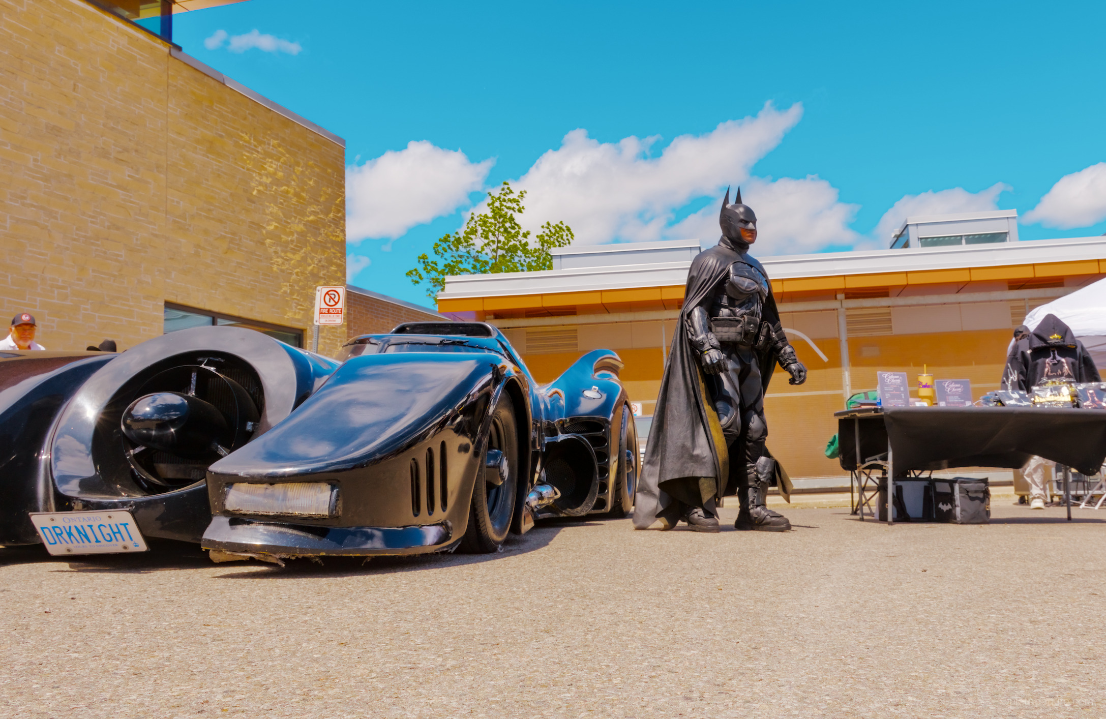 A costumed performer standing beside a black car at the Bread & Honey Festival.
